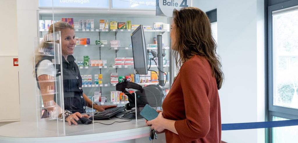 Medewerker en klant bij de balie in de apotheek