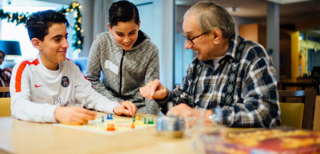 Oude man en jongeren spelen mens erger je niet