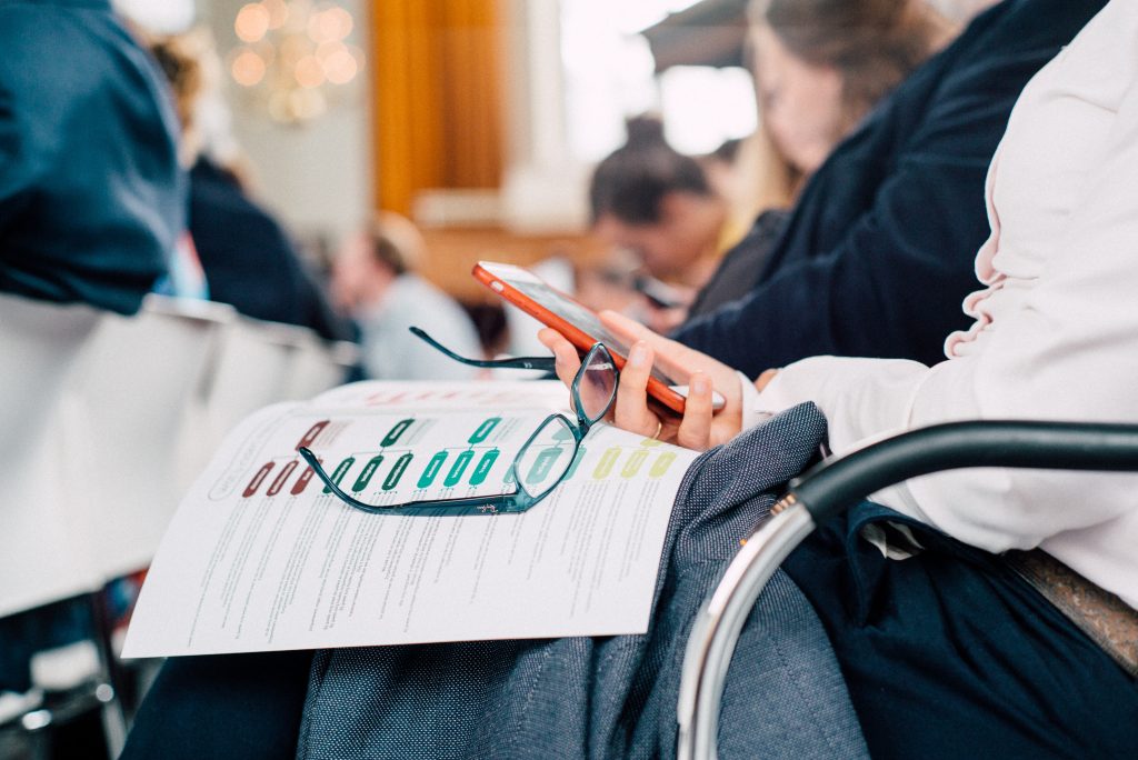 Iemand kijkt op smartphone en heeft papier op de schoot