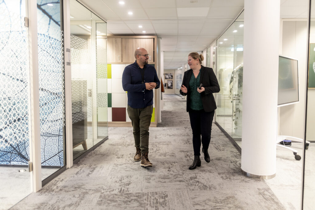Medewerkers lopen op de gang en zijn met elkaar in gesprek
